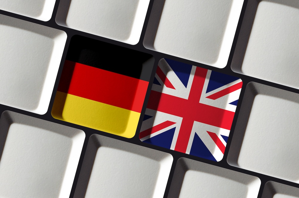 Deutsche und englische Flagge auf Tastatur als Symbol für Übersetzungen beim Deutsch- und Englischlernen.